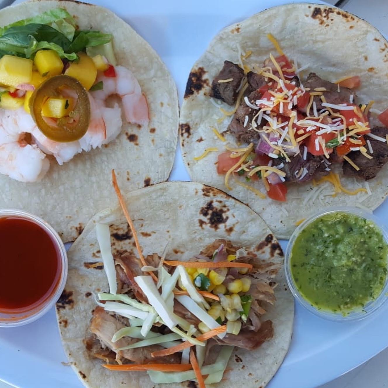 Three corn tortilla tacos with shrimp, steak and pork