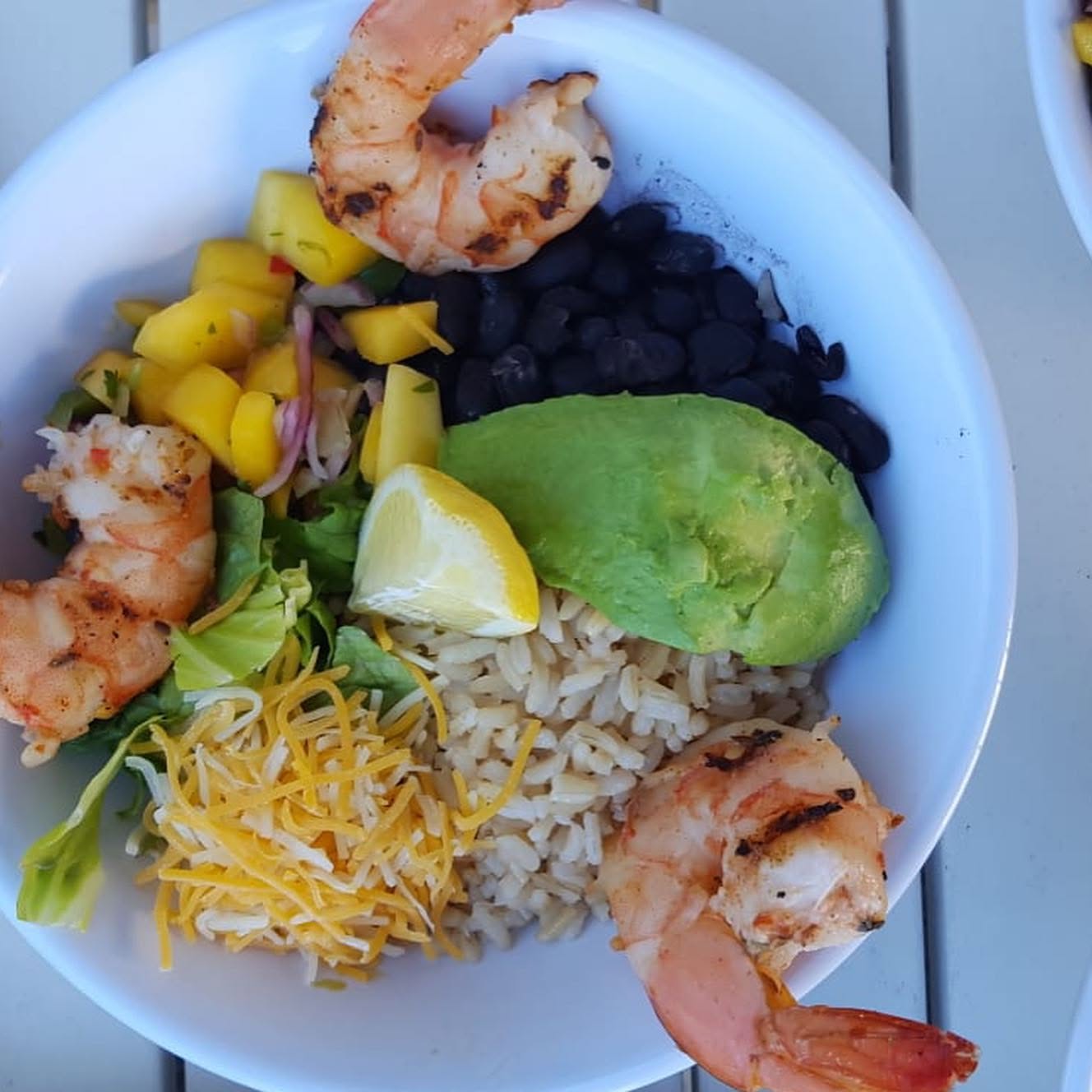 Rice bowl with grilled shrimp, black beans, avocado and mango salsa